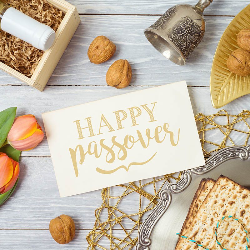 Jewish holiday Passover greeting card with matzo, seder plate, wine and tulip flowers on wooden table